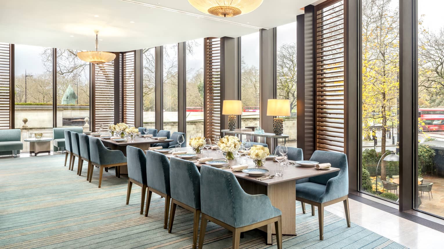 Two rectangular dining tables flanked with blue suede?covered chairs, set for a meal