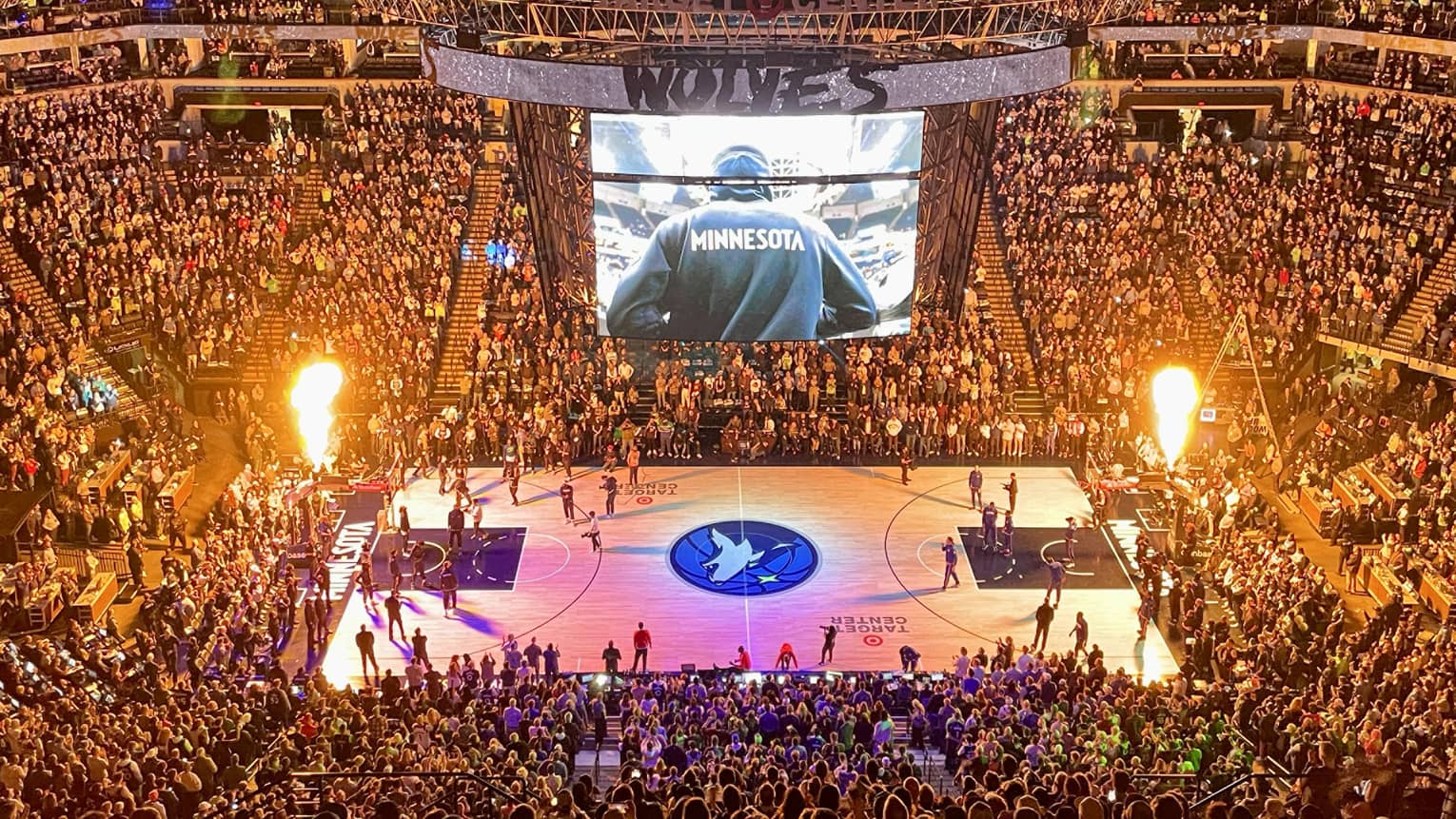 Large audience watching a basketball game with purple lights on the basketball court.