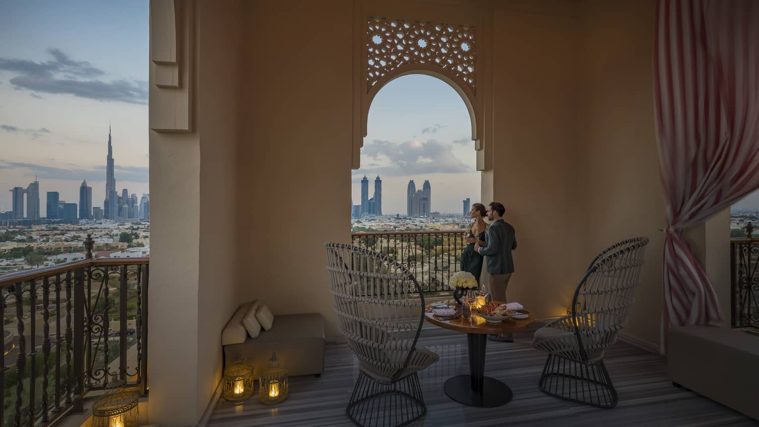 Couple gazing out at sunset city skyline from terrace archway