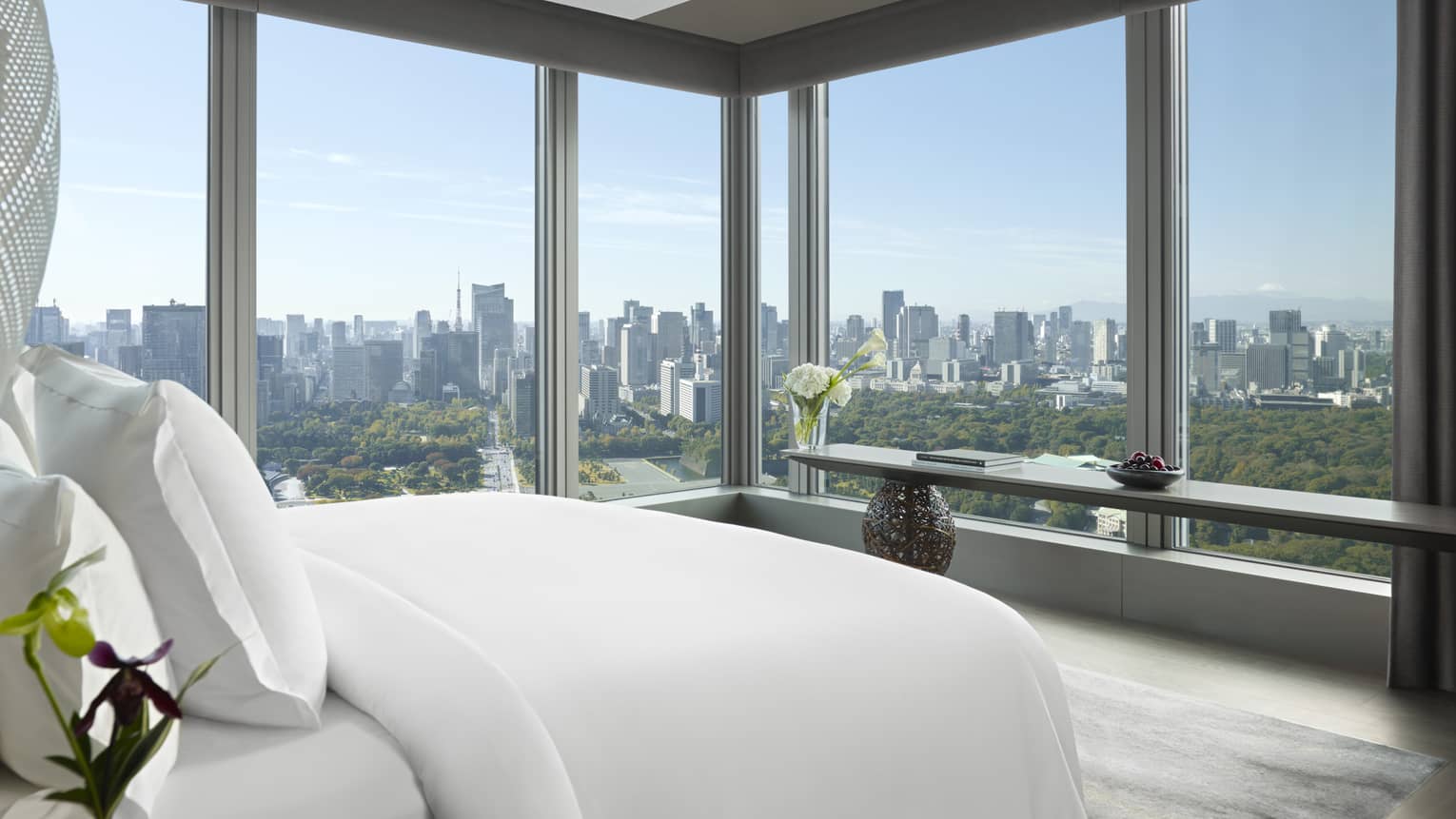 Tokyo suites bedroom with floor-to-ceiling windows offering panoramic city skyline view