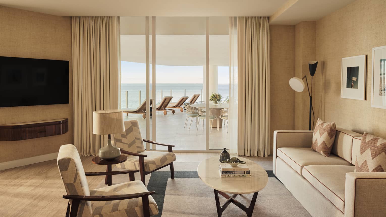 Living room with sofa, two arm chairs, TV, walk-out terrace with ocean view