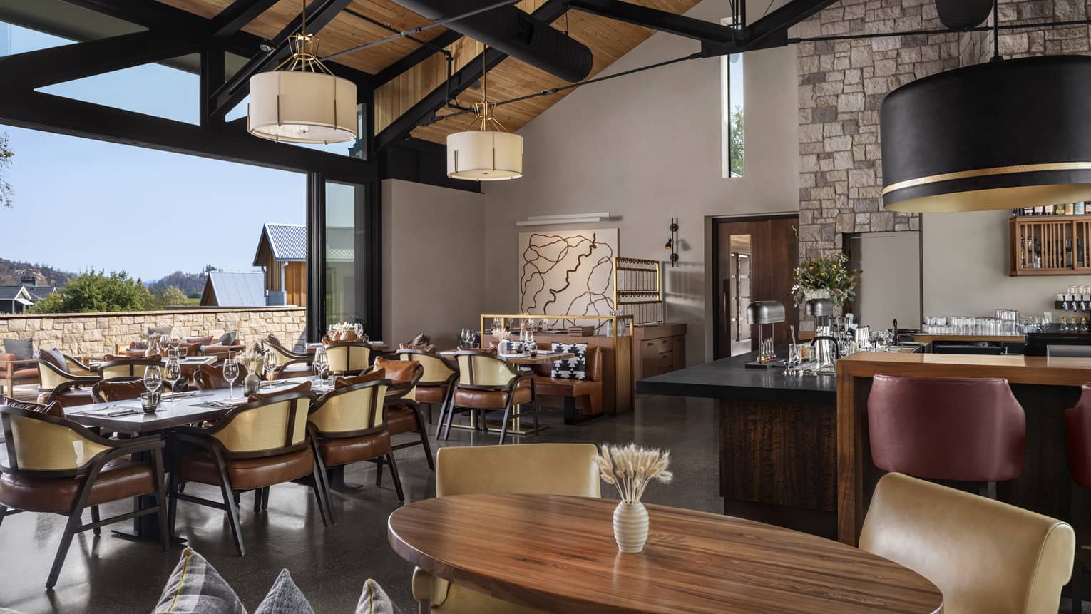 Restaurant with vaulted wooden ceiling, wooden tables and leather chairs, opens to the outdoors