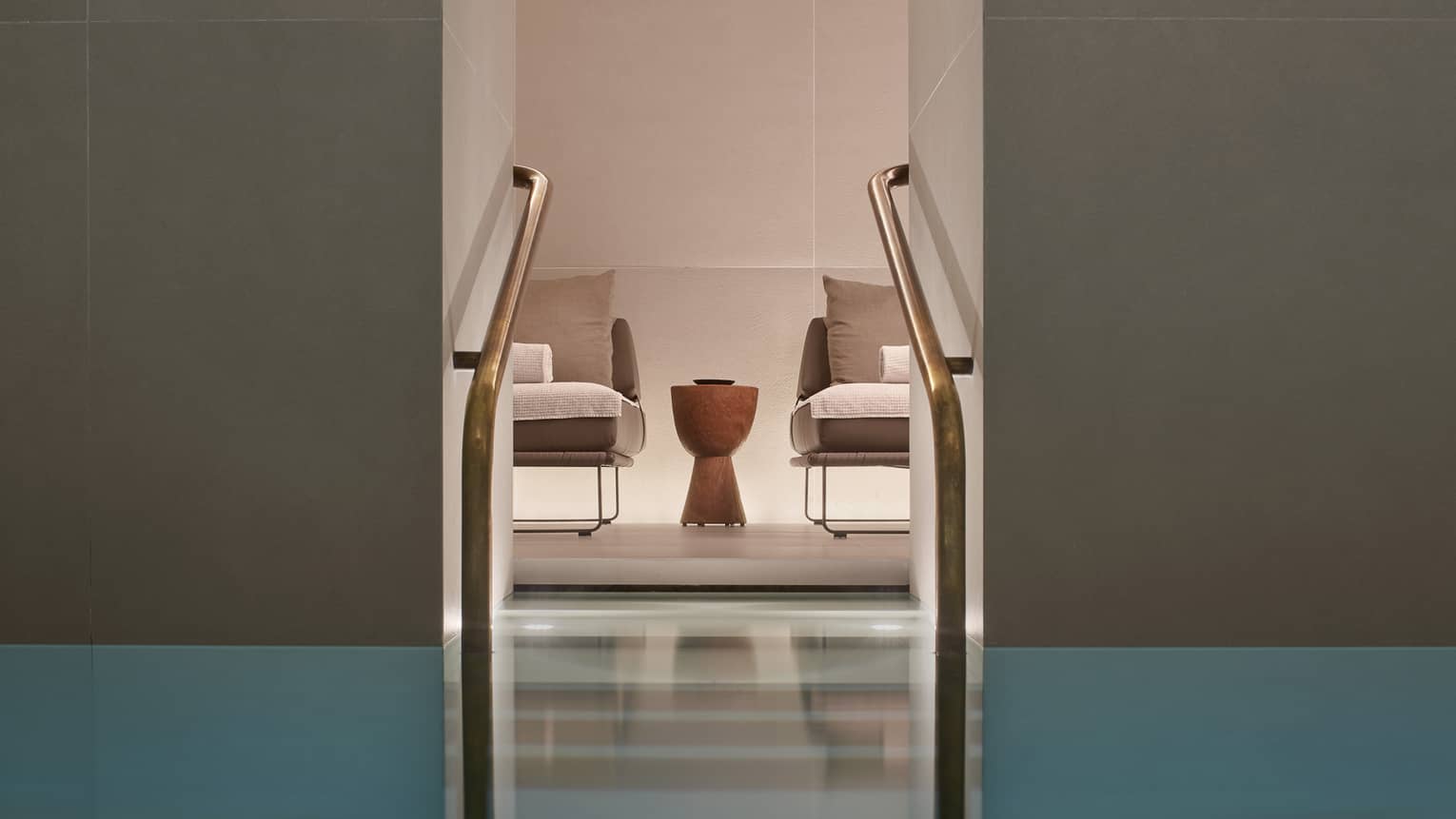 Two chairs and small table as seen from Milan Spa lap pool staircase with railings