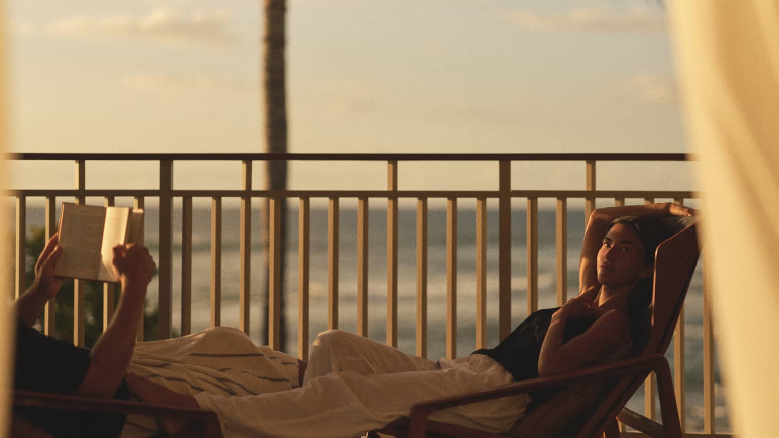 Two people lounge on ocean-view balcony