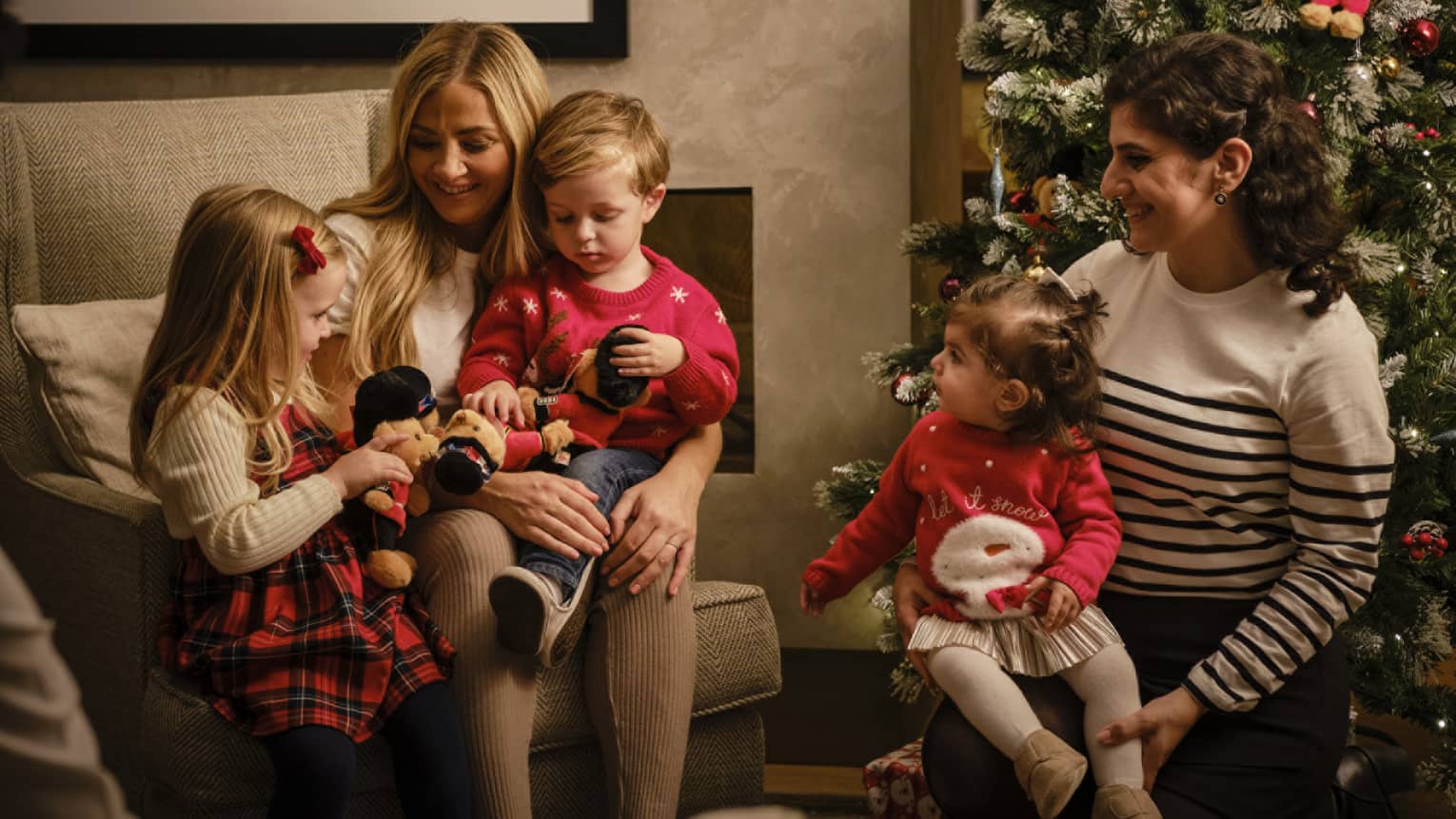 Family of five dressed for the holidays, seated and gathered around a Christmas tree