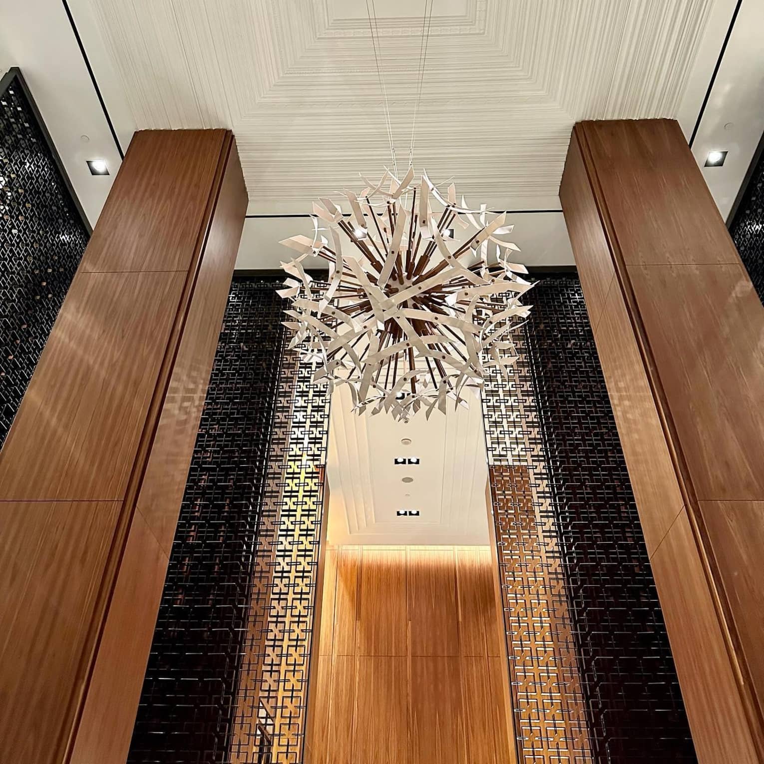 A large circular chandelier in a modern hotel lobby