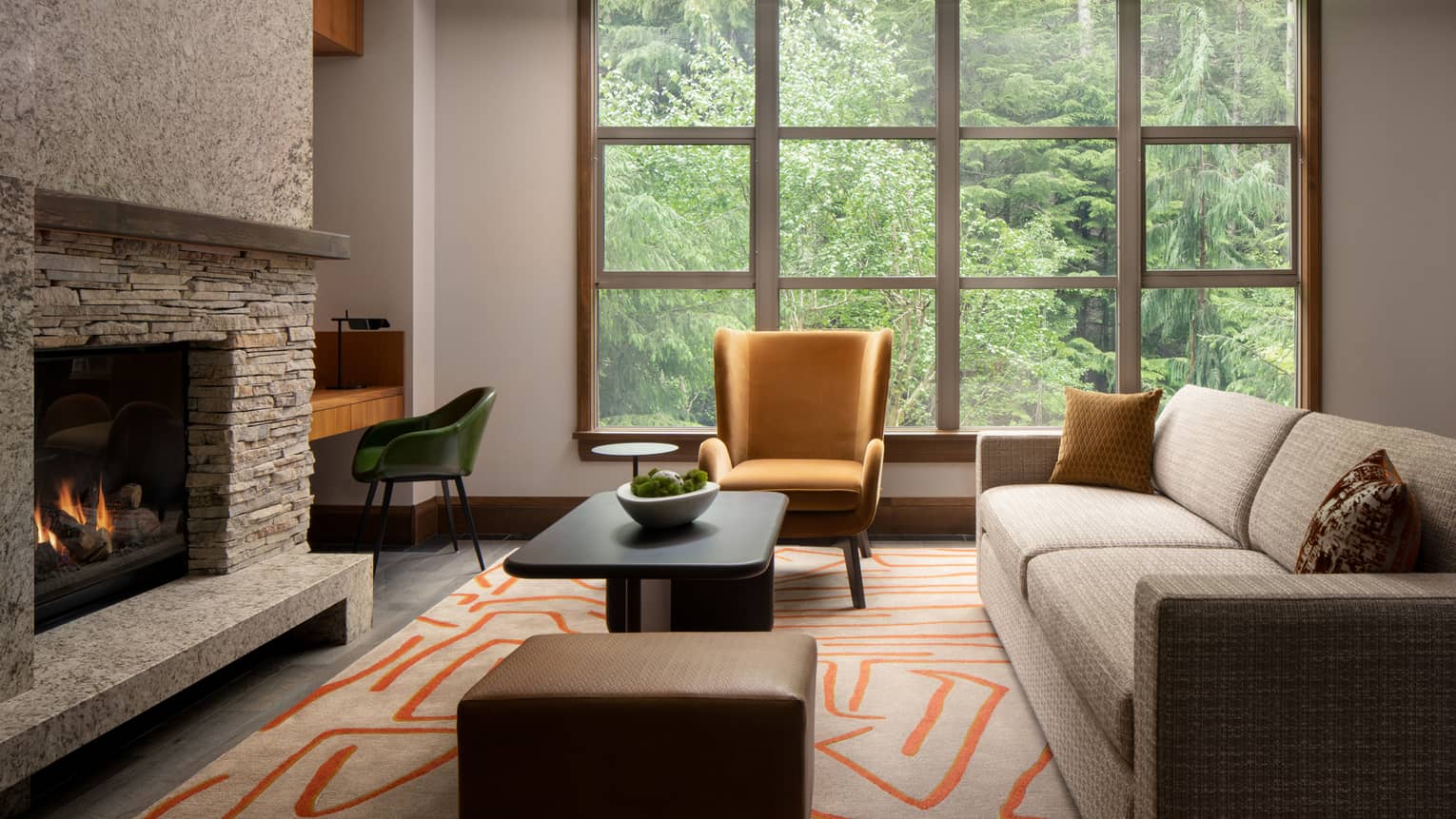 Elegant living area of a luxury vacation rental at Four Seasons Whistler. The room features a large window with a view of dense green trees, a stone fireplace, and modern furnishings. A beige sofa with decorative pillows, a mustard yellow armchair, a dark wood coffee table, and a geometric patterned rug add warmth and style to the space.,Elegant living area of a luxury vacation rental at Four Seasons Whistler. The room features a large window with a view of dense green trees, a stone fireplace, and modern furnishings. A beige sofa with decorative pillows, a mustard yellow armchair, a dark wood coffee table, and a geometric patterned rug add warmth and style to the space.