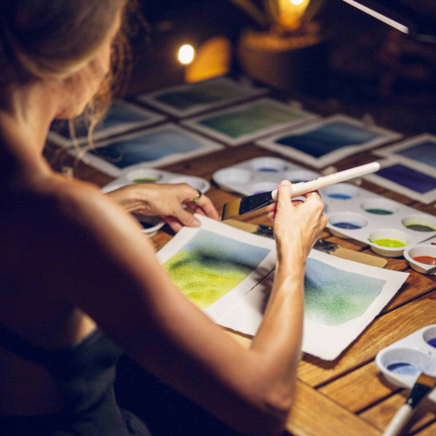 A woman painting a landscape on white paper with a brush