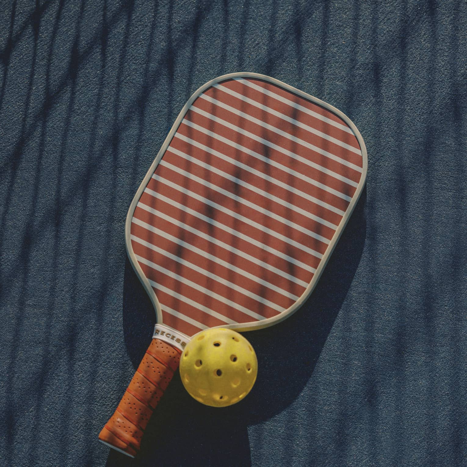 A pickleball paddle and yellow ball