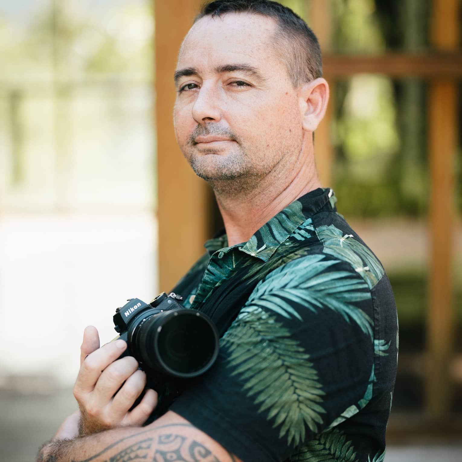 Photographer Vincent Brossault poses with his arms crossed, one hand holding a camera against his chest.
