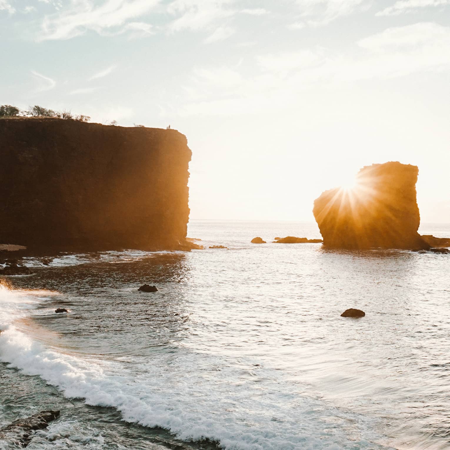 Sun sets over large rocks in lagoon