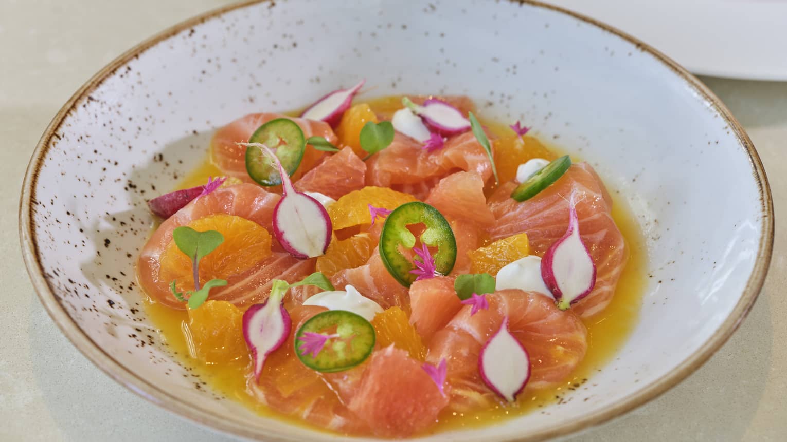 Bowl of citrus sections with sliced jalepeno and radishes in citrus juice