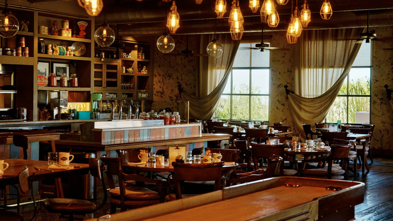 Proof restaurant with shuffleboard table and hanging lights, at Four Seasons Resort Scottsdale