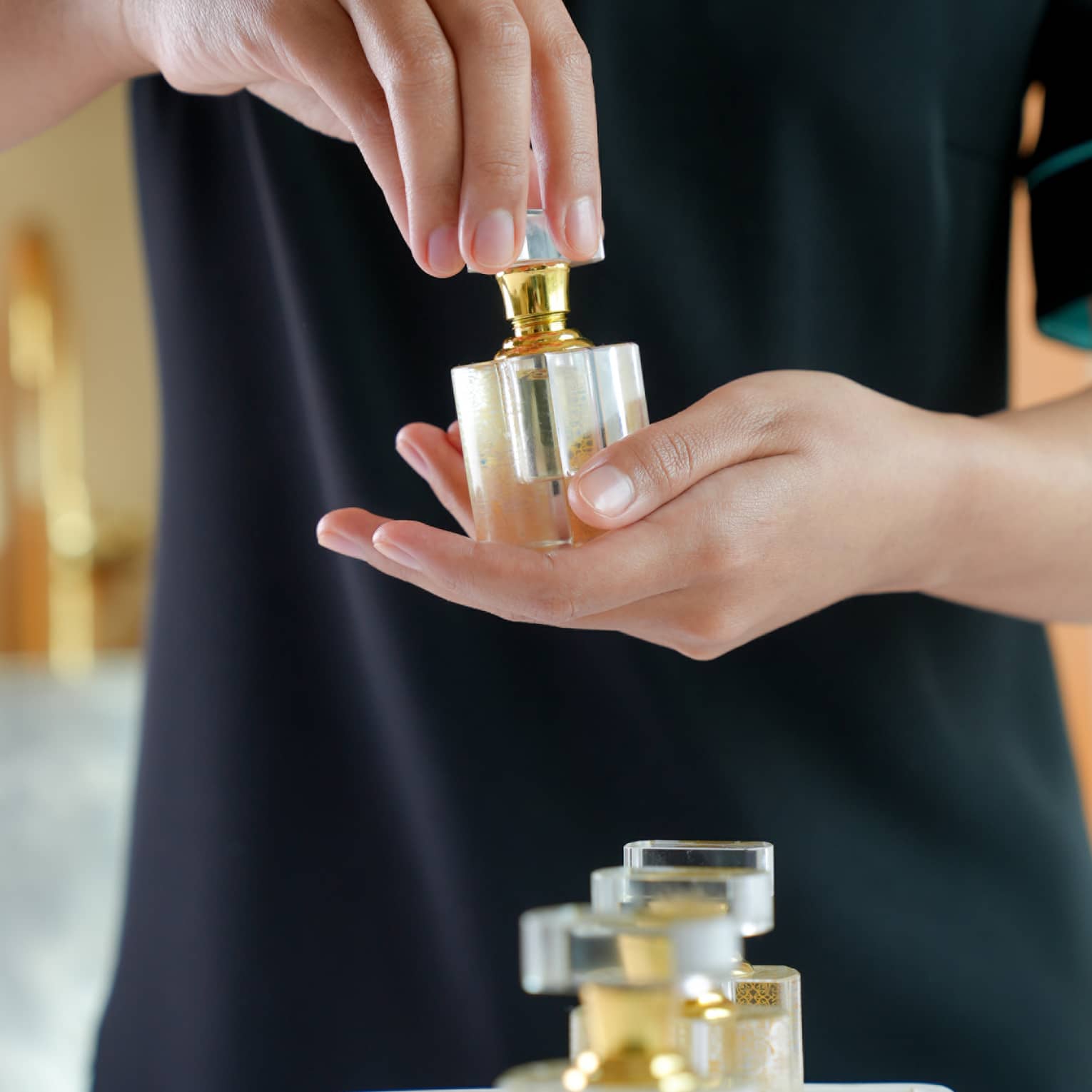 A spa attendant holding a square, glass fragrance bottle