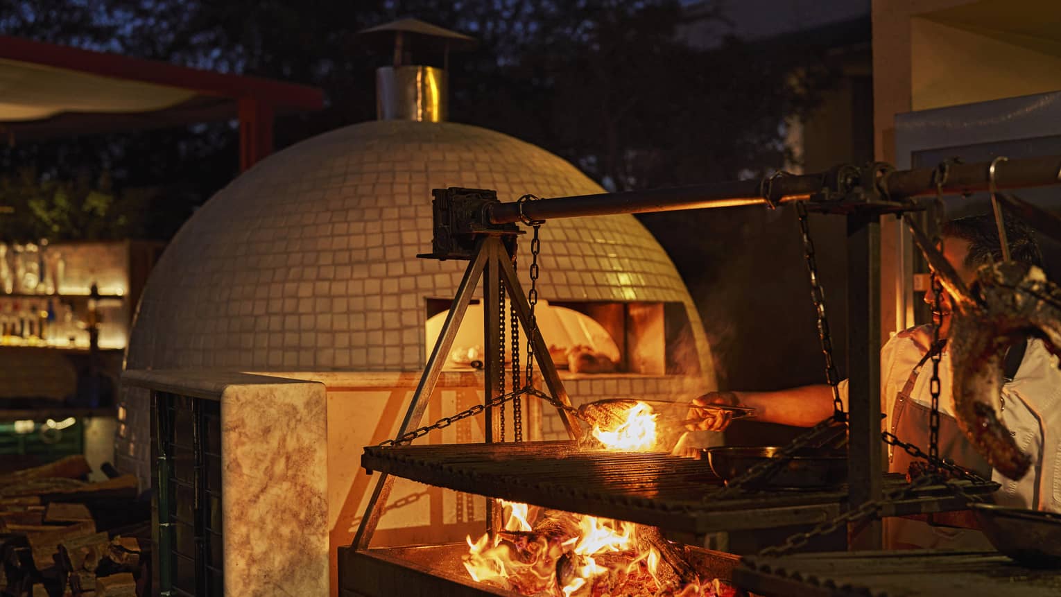 Wood-fired pizza oven and open fire in outdoor kitchen