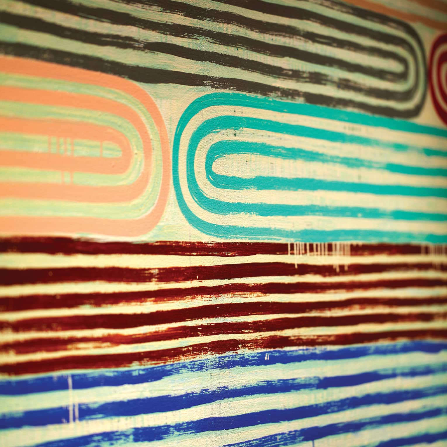 Close-up of pink, teal, red and blue lines of paint in pattern on canvas