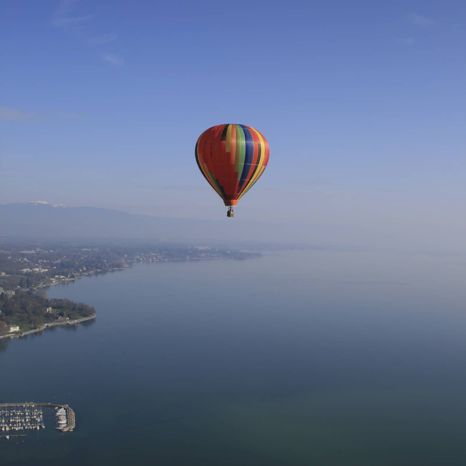 Colourful striped hot air balloon floating over Lake Geneva
