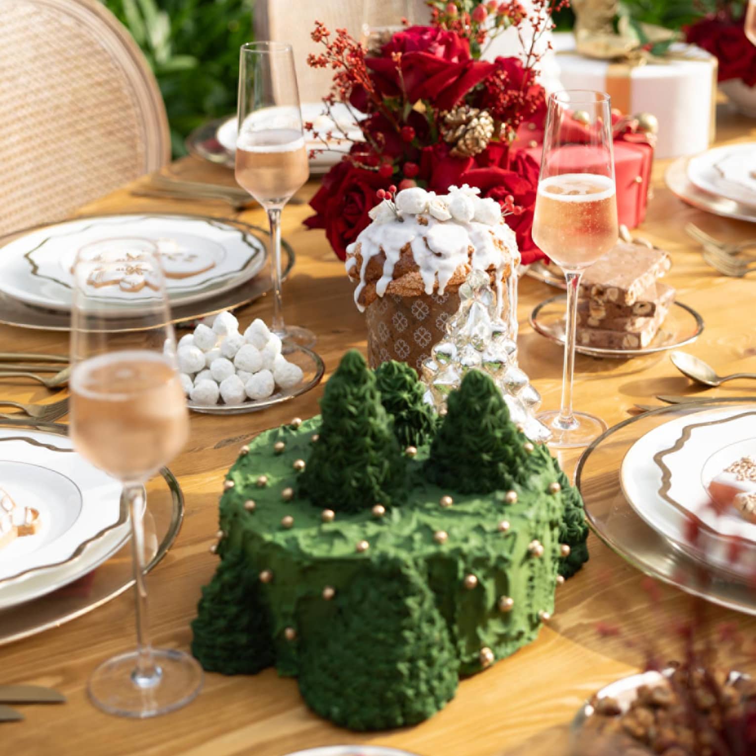 Table set for Christmas with green cake and red flowers and glasses of champagne