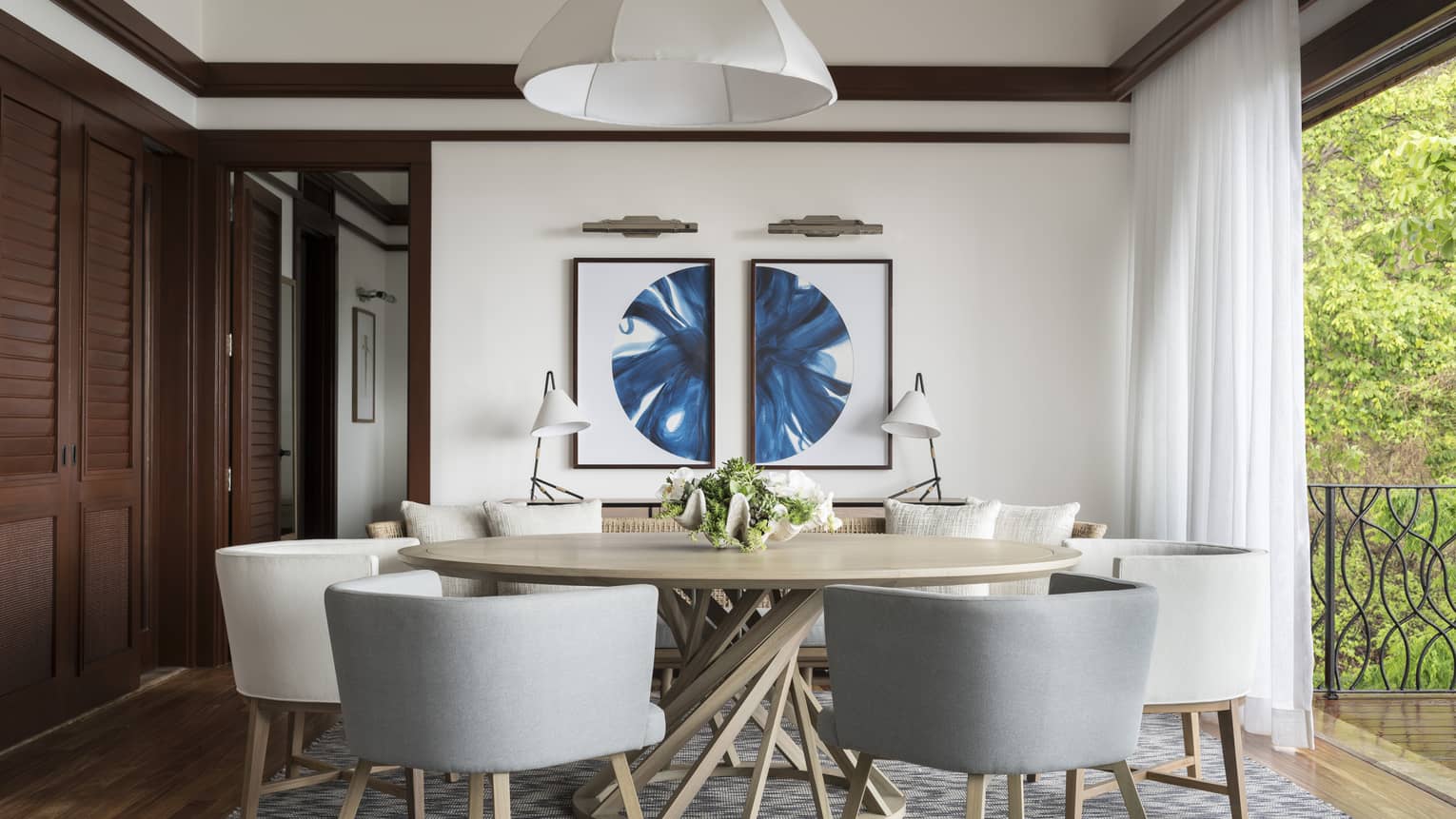 Grey and white mid-century style dining chairs and round dining table by floor-to-ceiling window