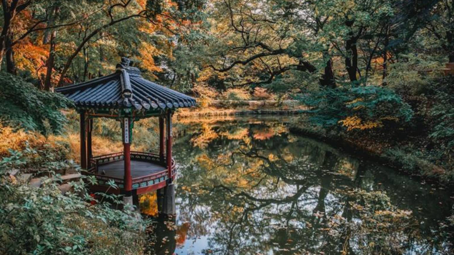 Small overwater gazebo at lake surrounded by autumn foliage