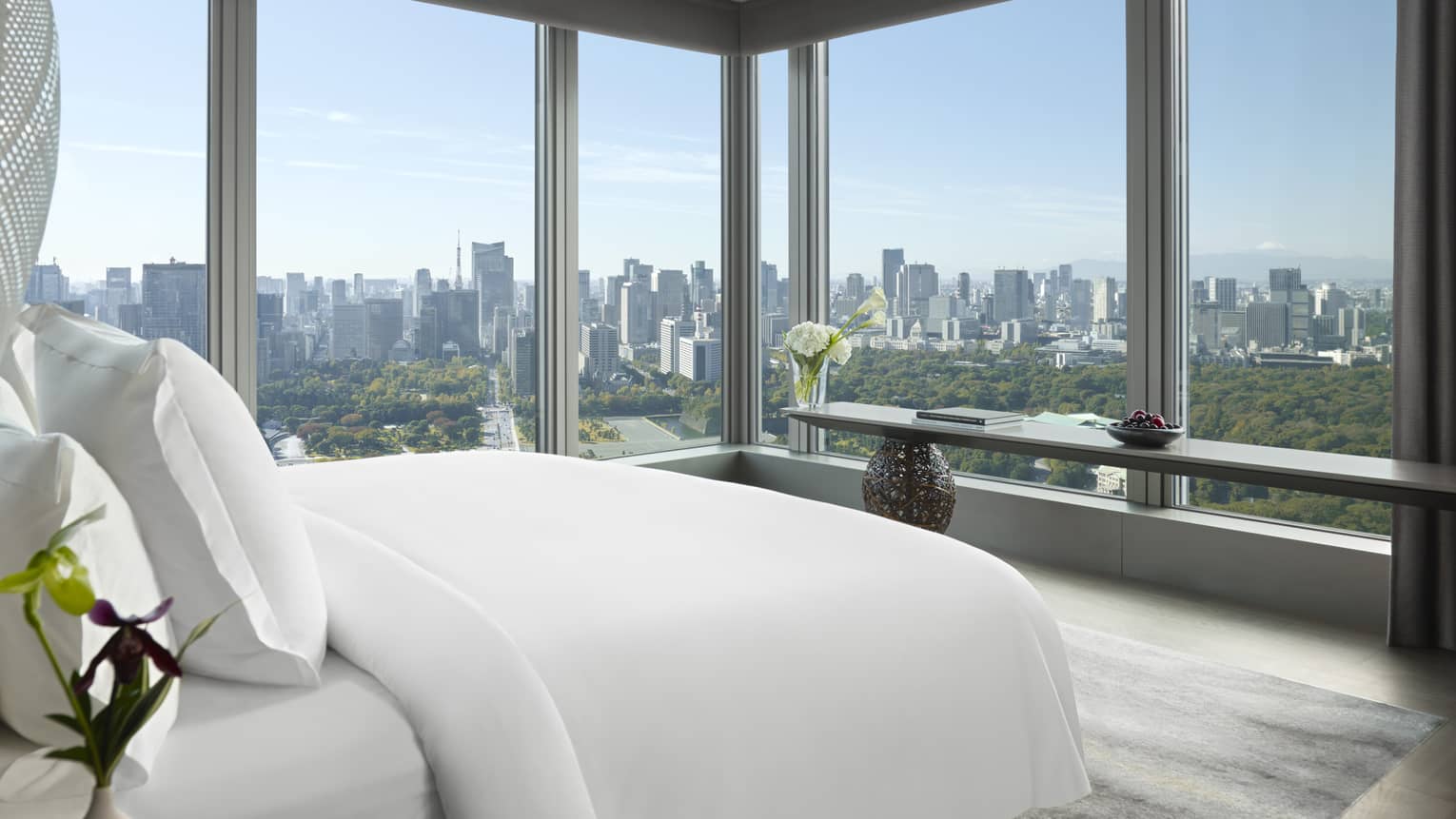 Tokyo suites bedroom with floor-to-ceiling windows offering panoramic city skyline view