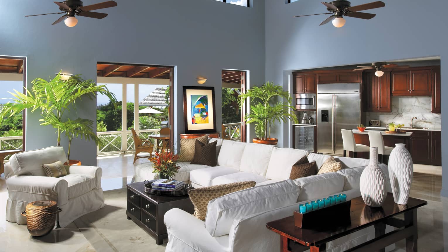 Plush white sofas by wood table, modern white vases, kitchen in background