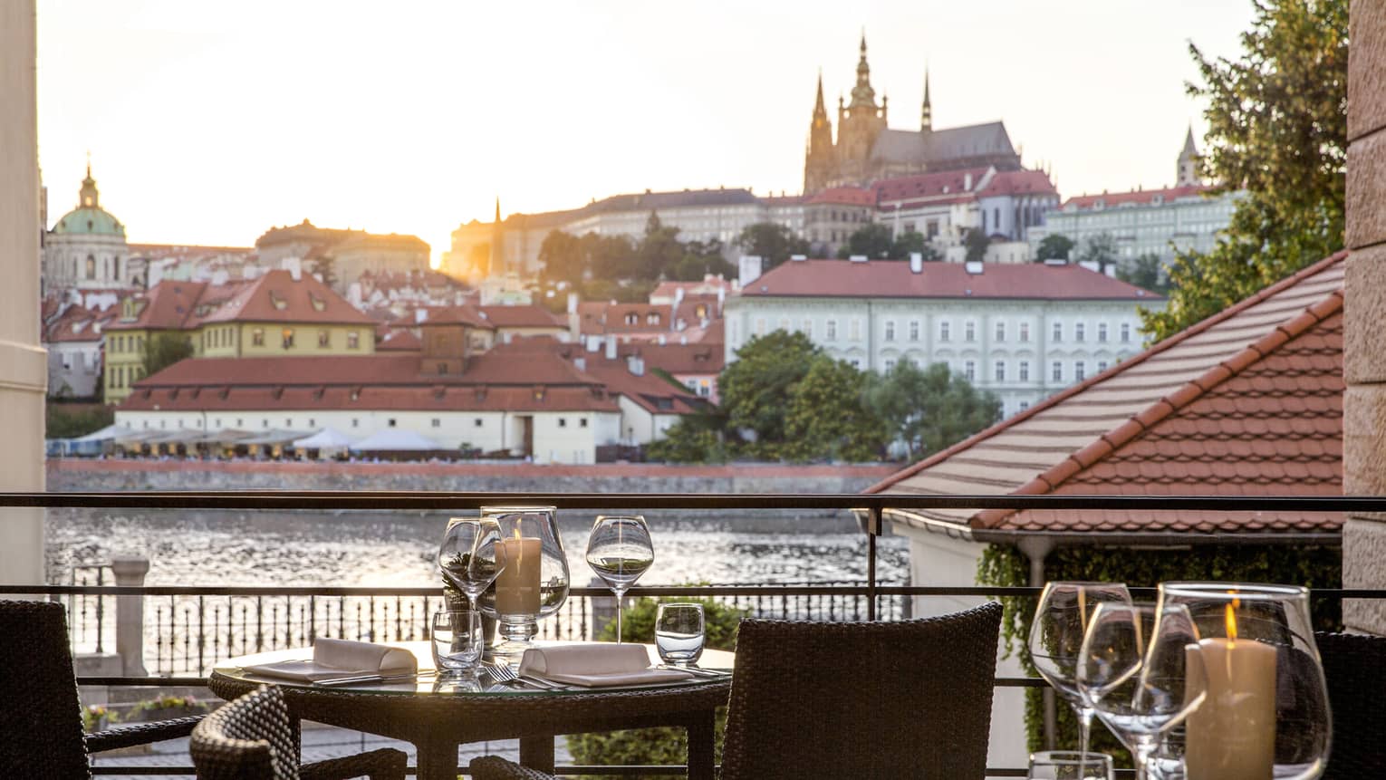 Outdoor dining table on patio overlooking river as sun starts to set