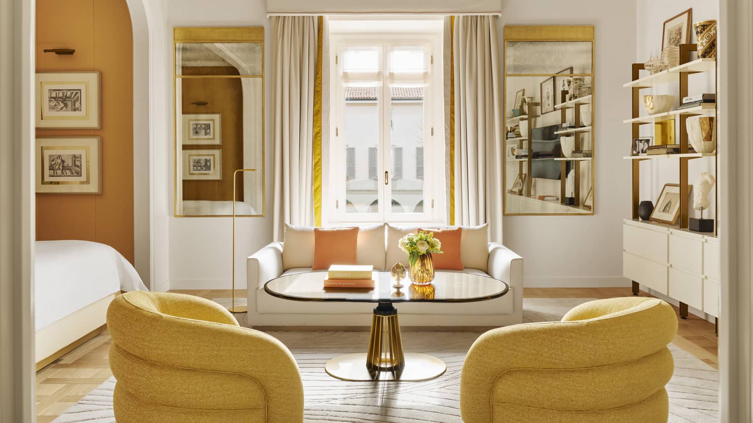 Luxury hotel suite with frescoed ceiling and modern yellow arm chairs, white sofa and adjacent bedroom