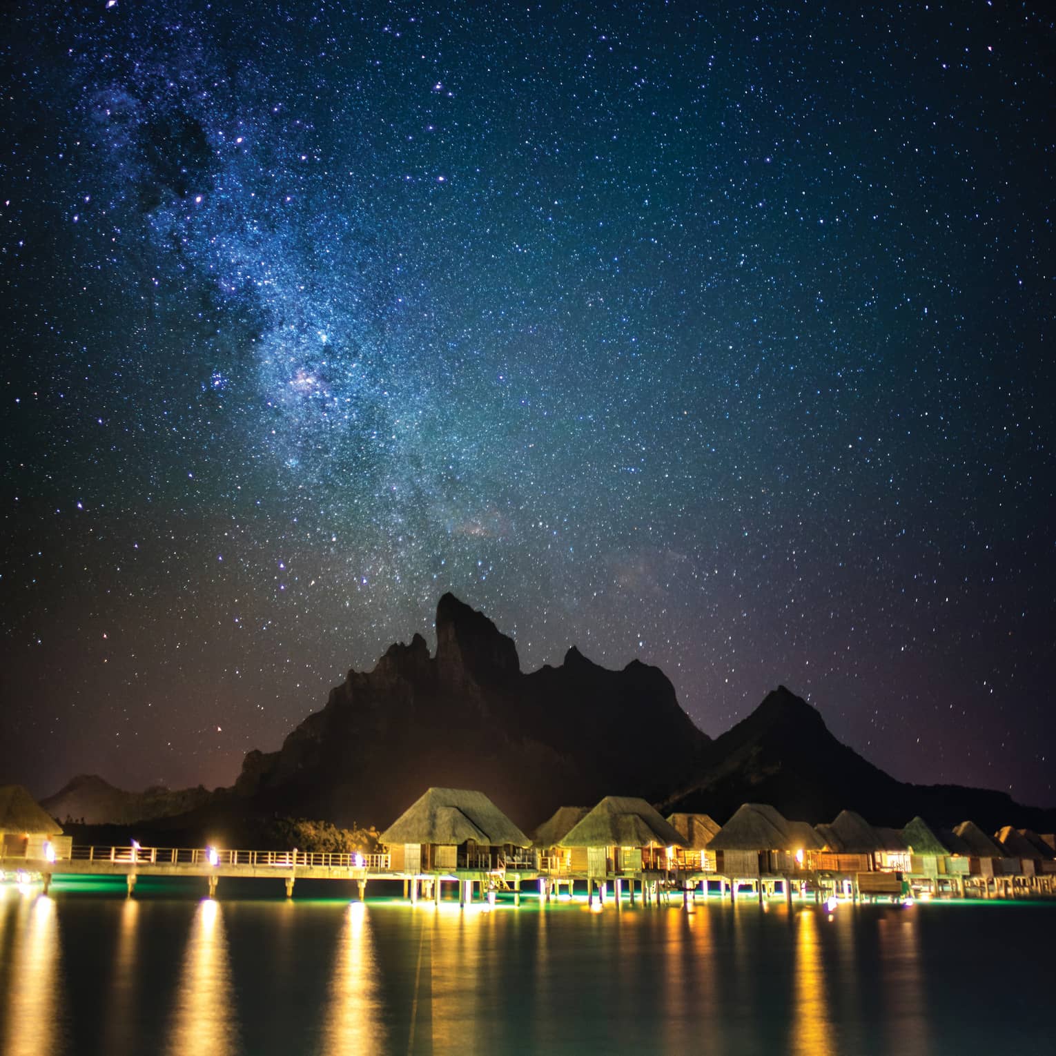 Illuminated Four Seasons Resort Bora Bora beneath a blanket of stars at night