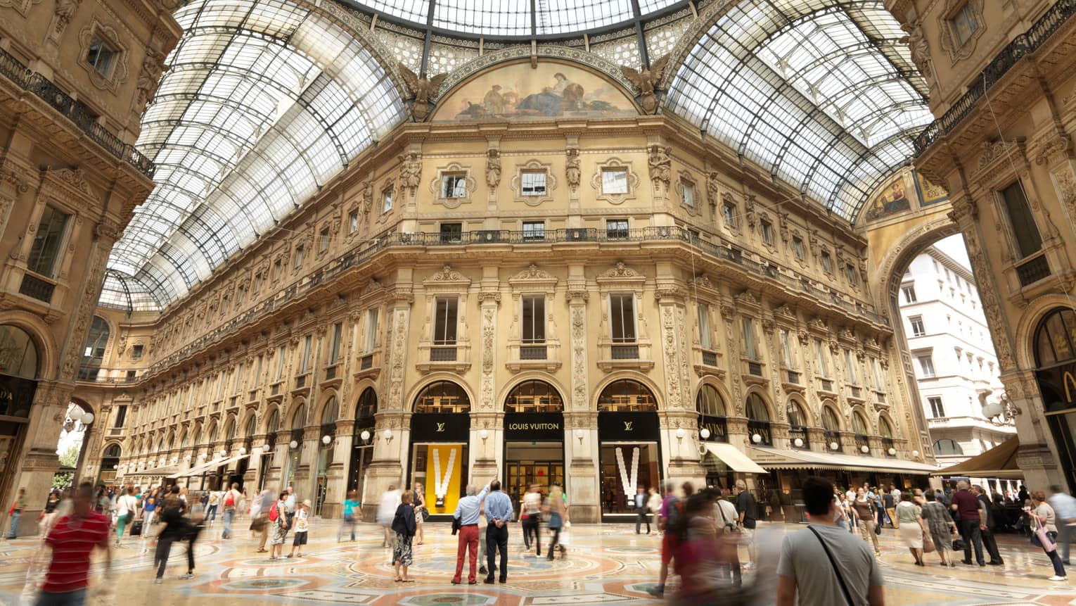 Shoppers gathered in historic Galleria Vittorio Emanuele building with soaring ceilings, shops