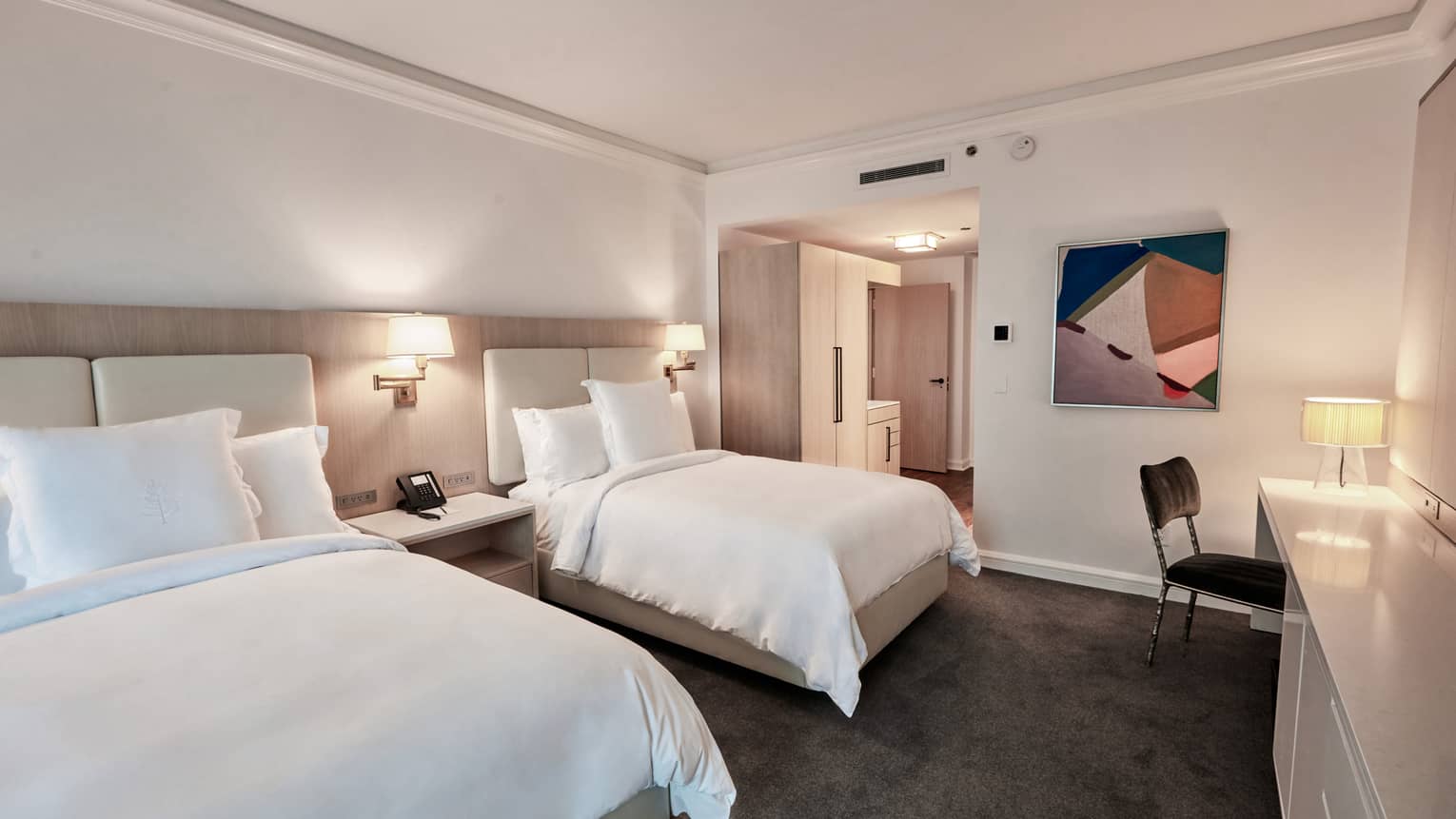 Hotel room with two white double beds, dark grey carpet, white walls