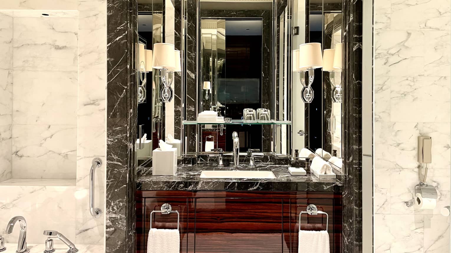 Marble bathroom with black marble accents surrounding the vanity, at Four Seasons Hotel Bahrain Bay