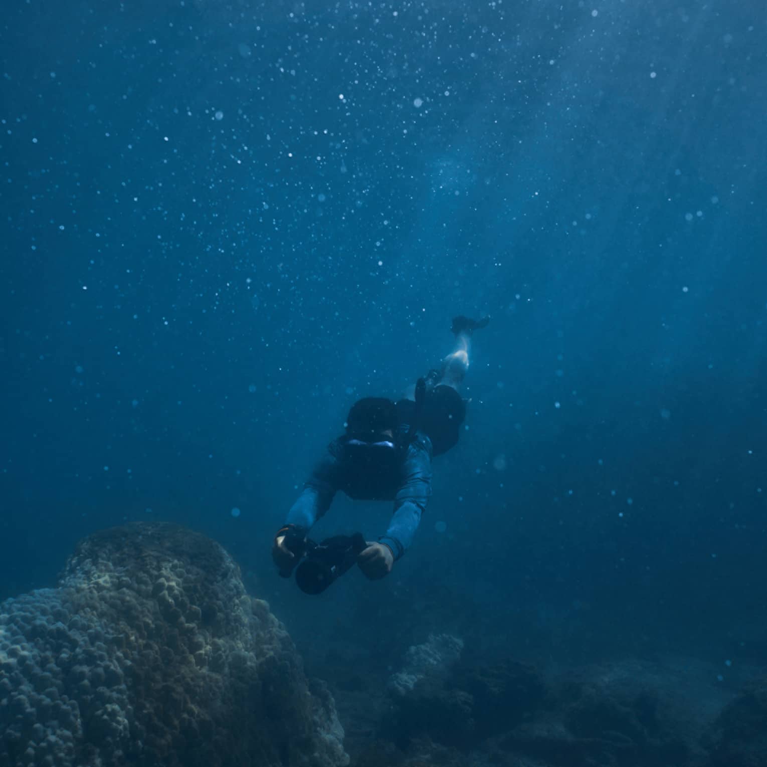 Person diving beneath the water using dive scooter