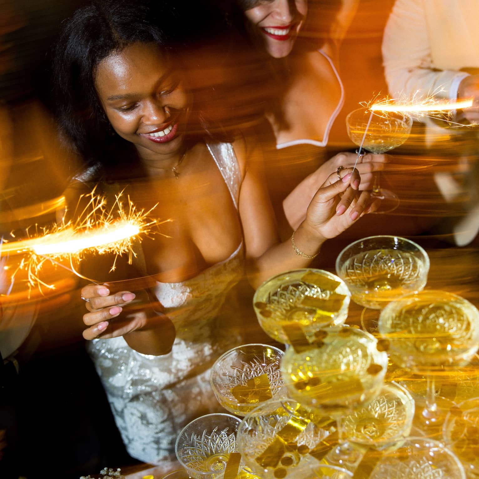 Two women dance in front of champagne tower