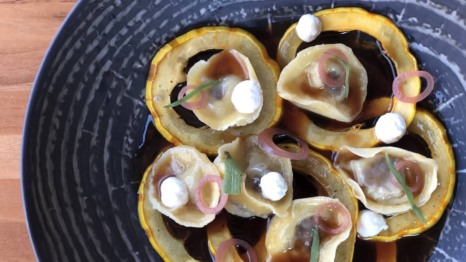Ricotta Tortellini on round vegetable slices on black plate