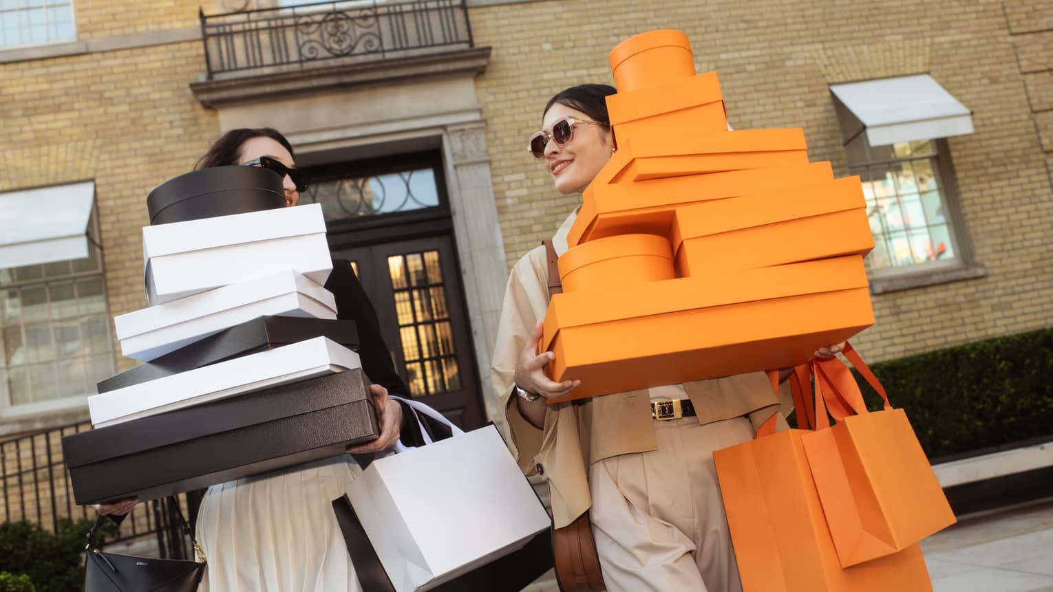 Two women carry many shopping bags and boxes