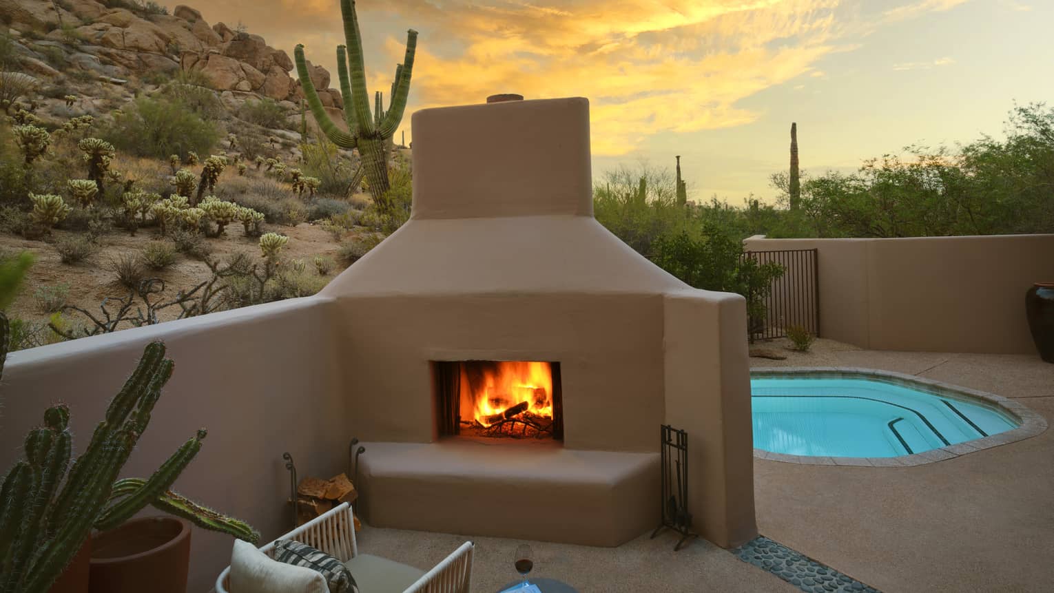 A pool beside a fire pit with a chair, surrounded by desert views