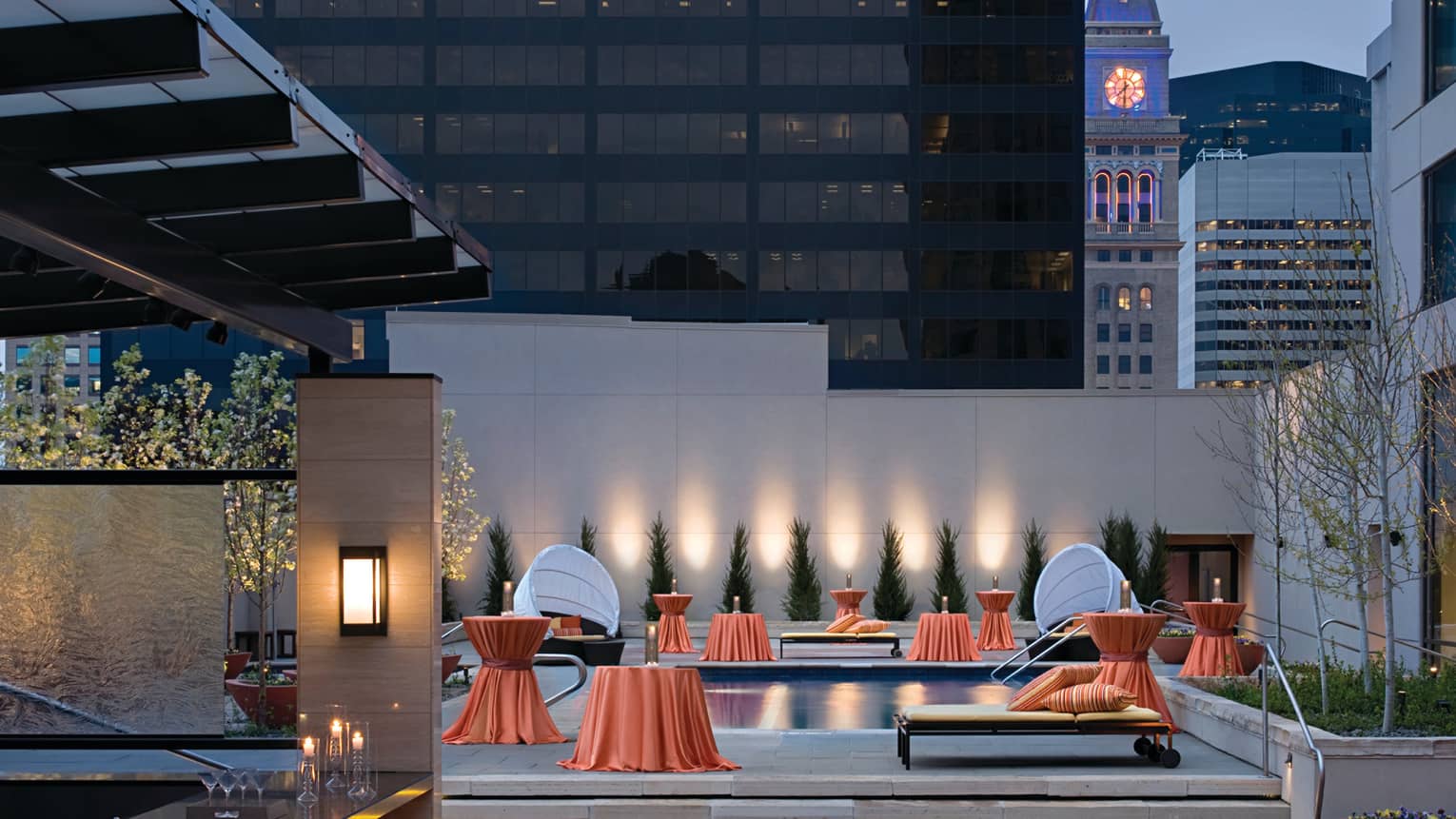 Rooftop bar, orange linens over small tables around outdoor pool