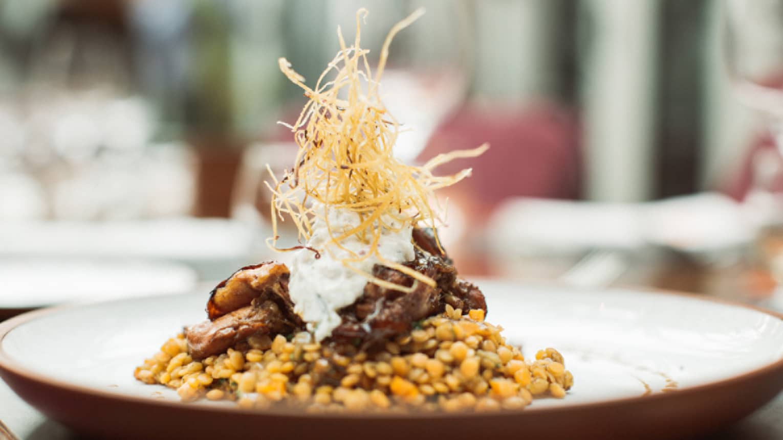 Braided lamb is served on top of Turkish lentils and topped with crispy onion