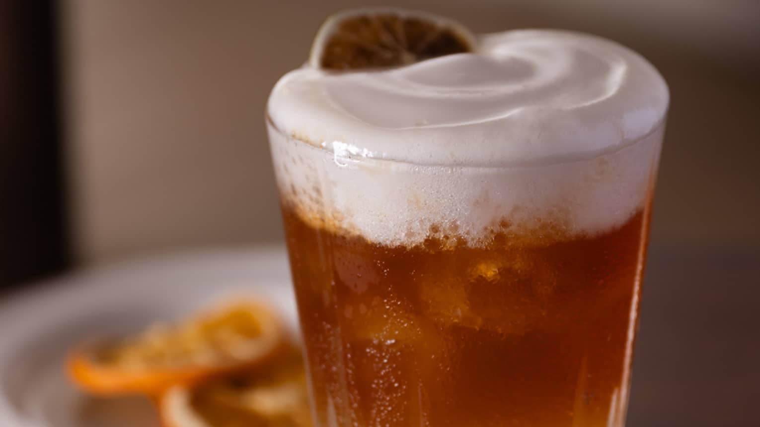 Glass of beer with slice of orange on top.