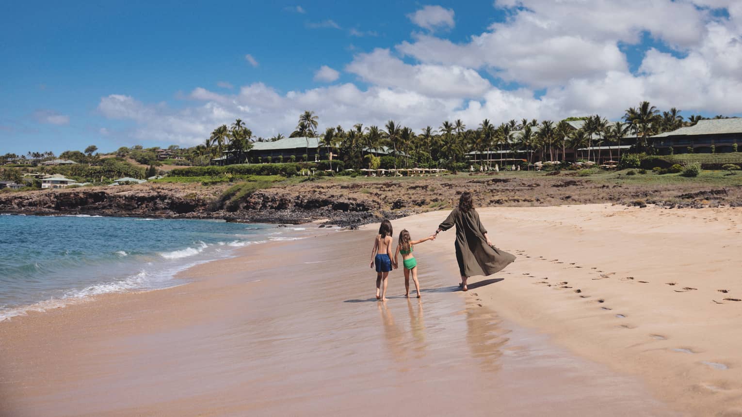 Woman and two kids walk on the beach