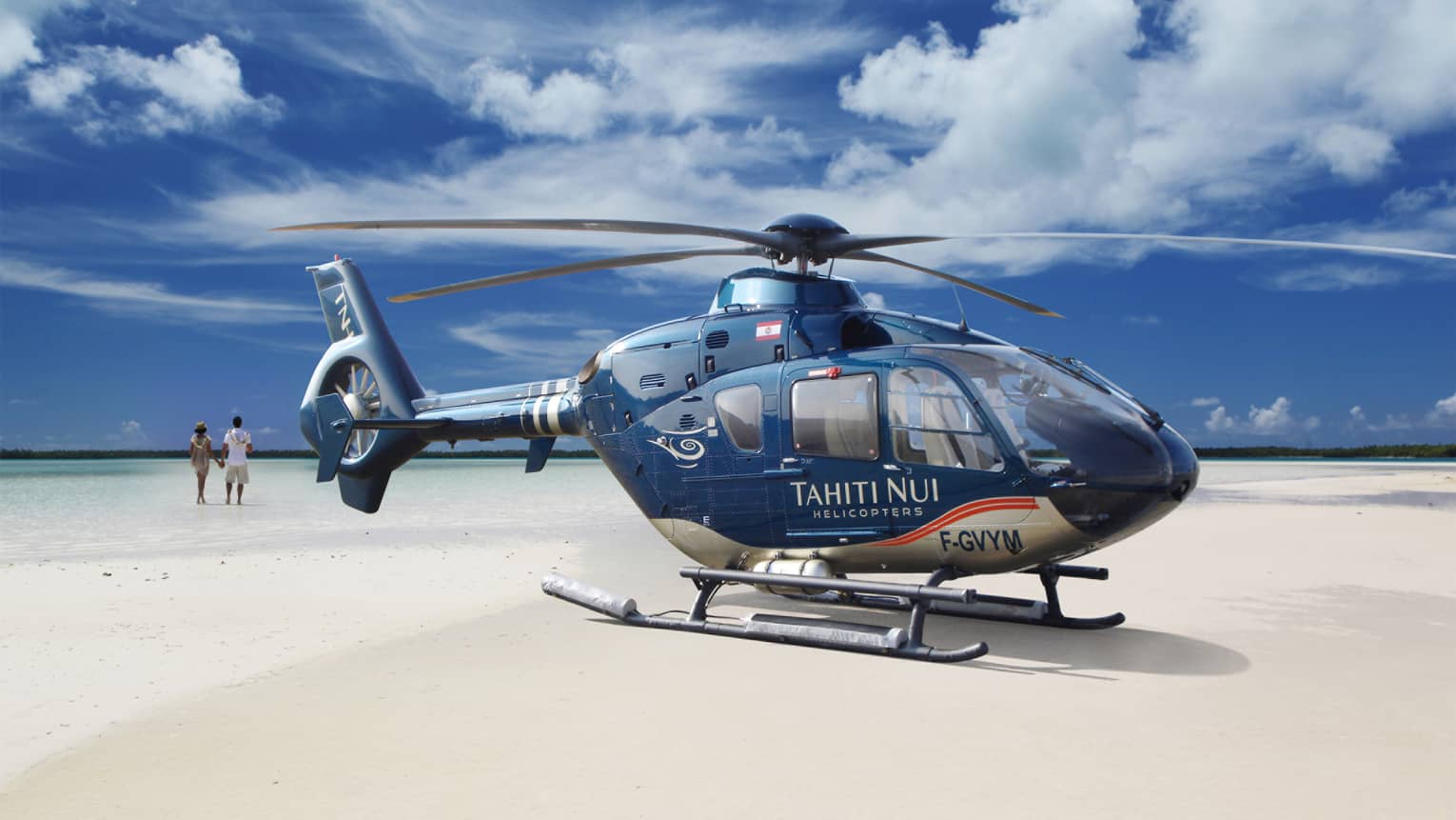 Guests walk on the beach before boarding the Tahiti Nui Helicopter for an island tour