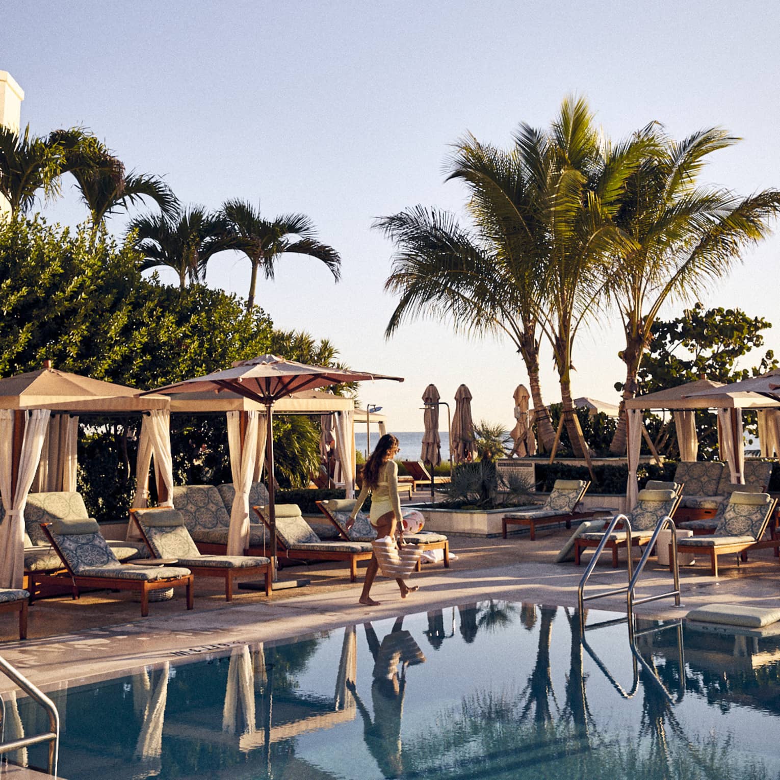 Guest walks by a row of poolside cabanas