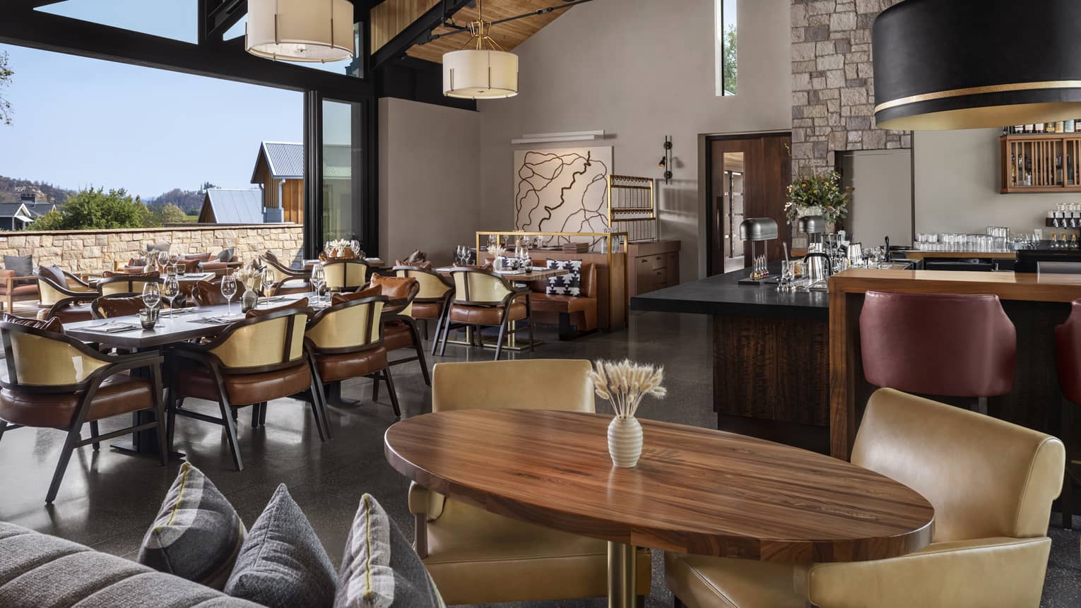 Restaurant with vaulted wooden ceiling, wooden tables and leather chairs, opens to the outdoors