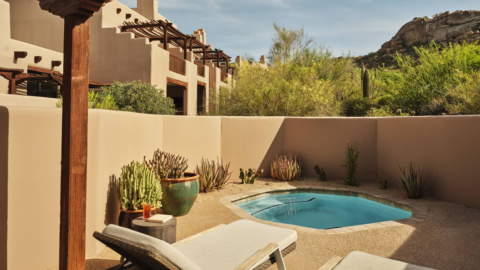 Plunge pool and two sun loungers on a walled-in terrace surrounded by desert landscape