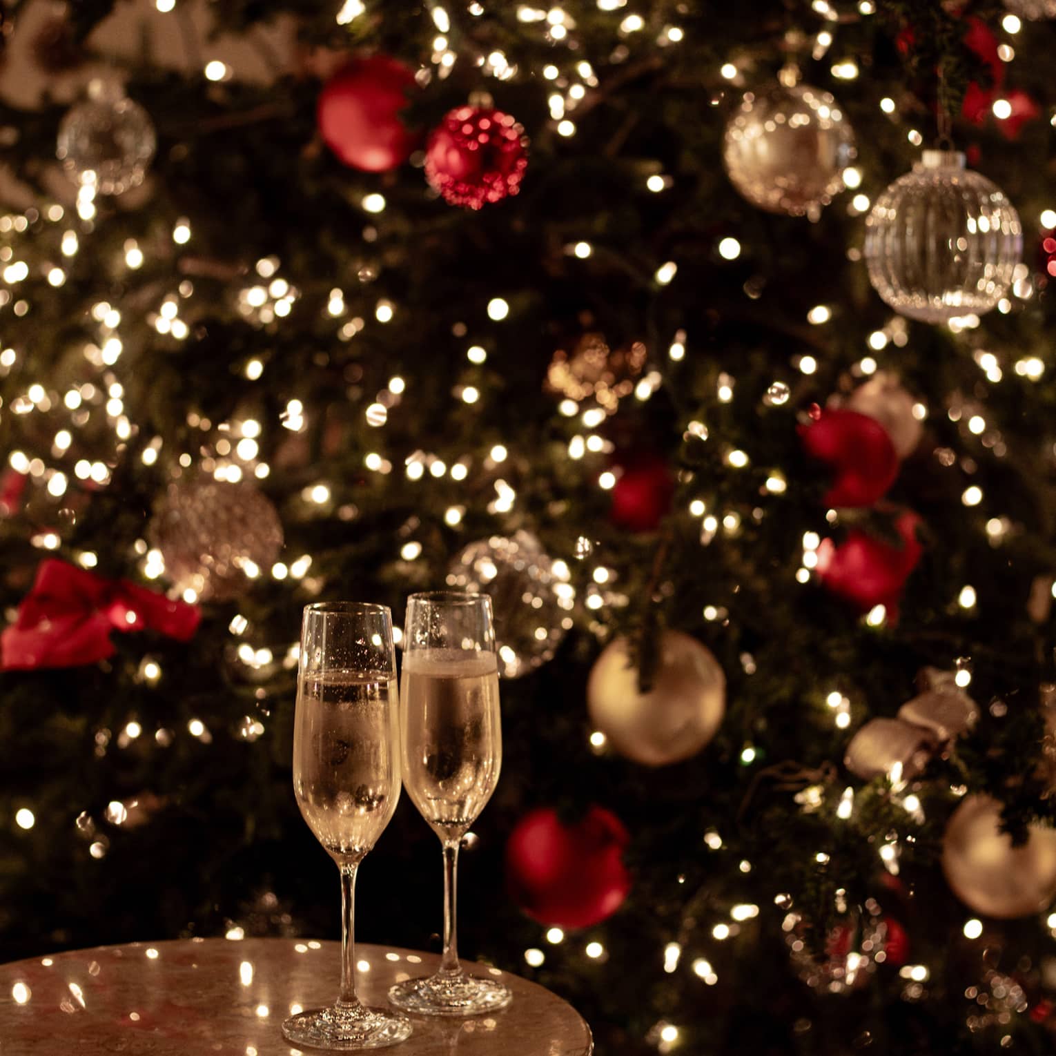 Joyous champagne toast with festive lights for Tokyo Christmas and New Year’s Eve celebrations.