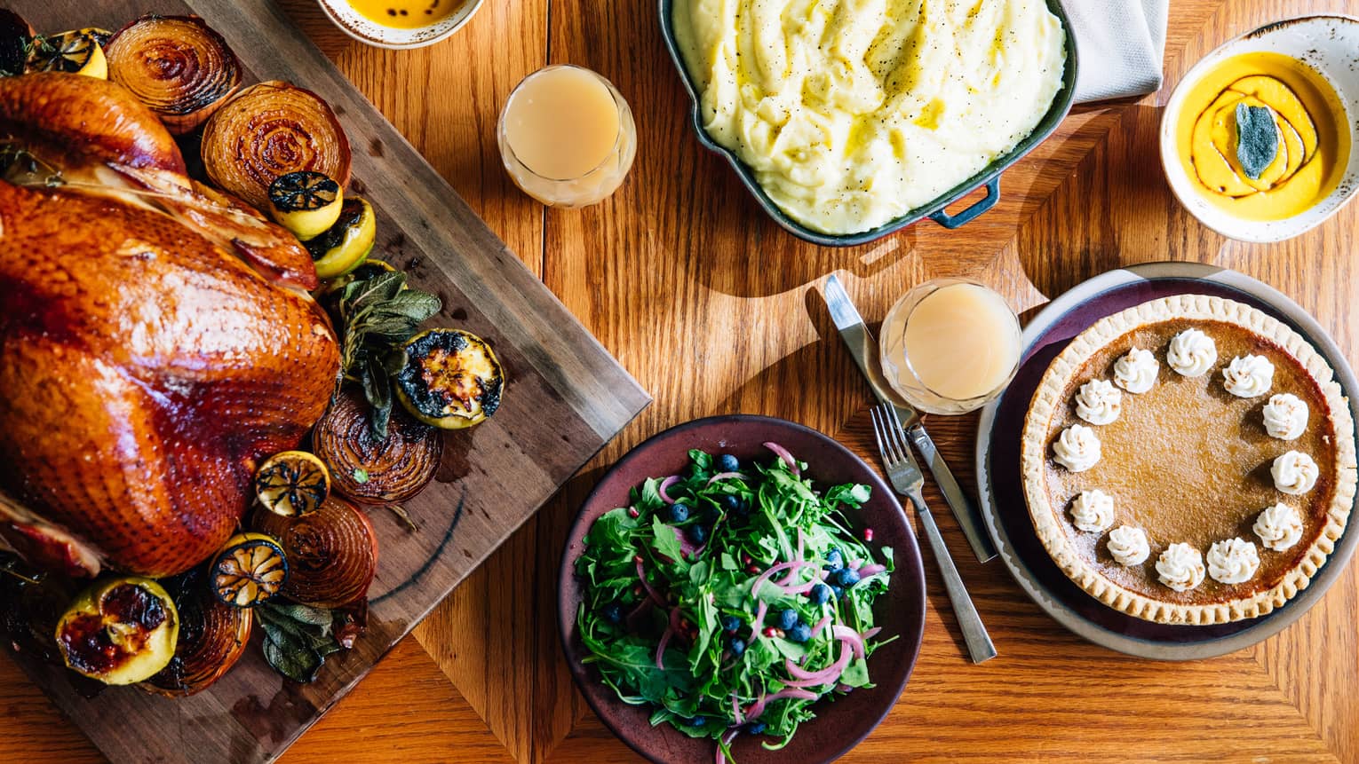 An aerial shot of a thanksgiving dinner including a roasted turkey with vegetables, mashed potatoes, salad and pumpkin pie