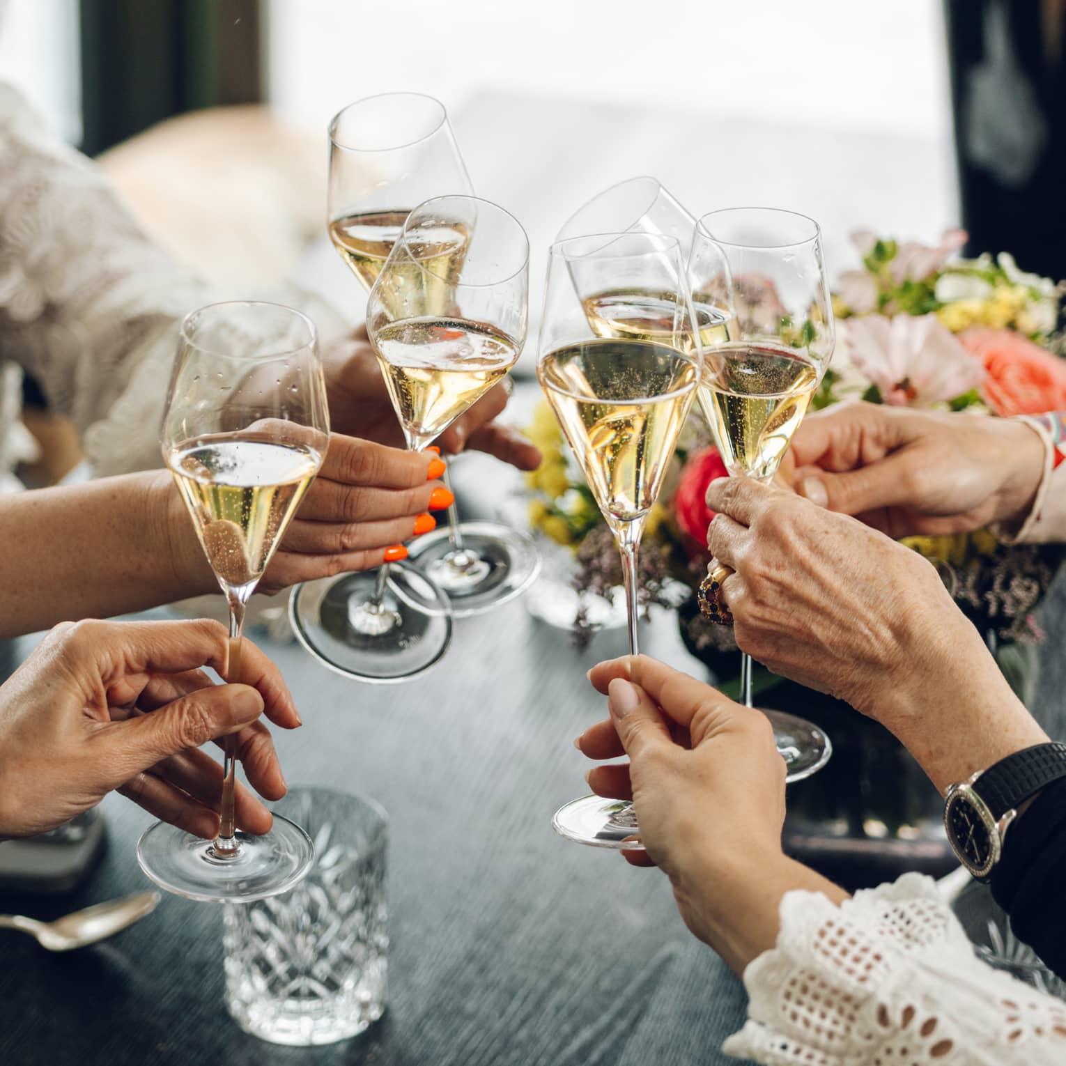 A group of guests toast glasses of champagne at a dining table