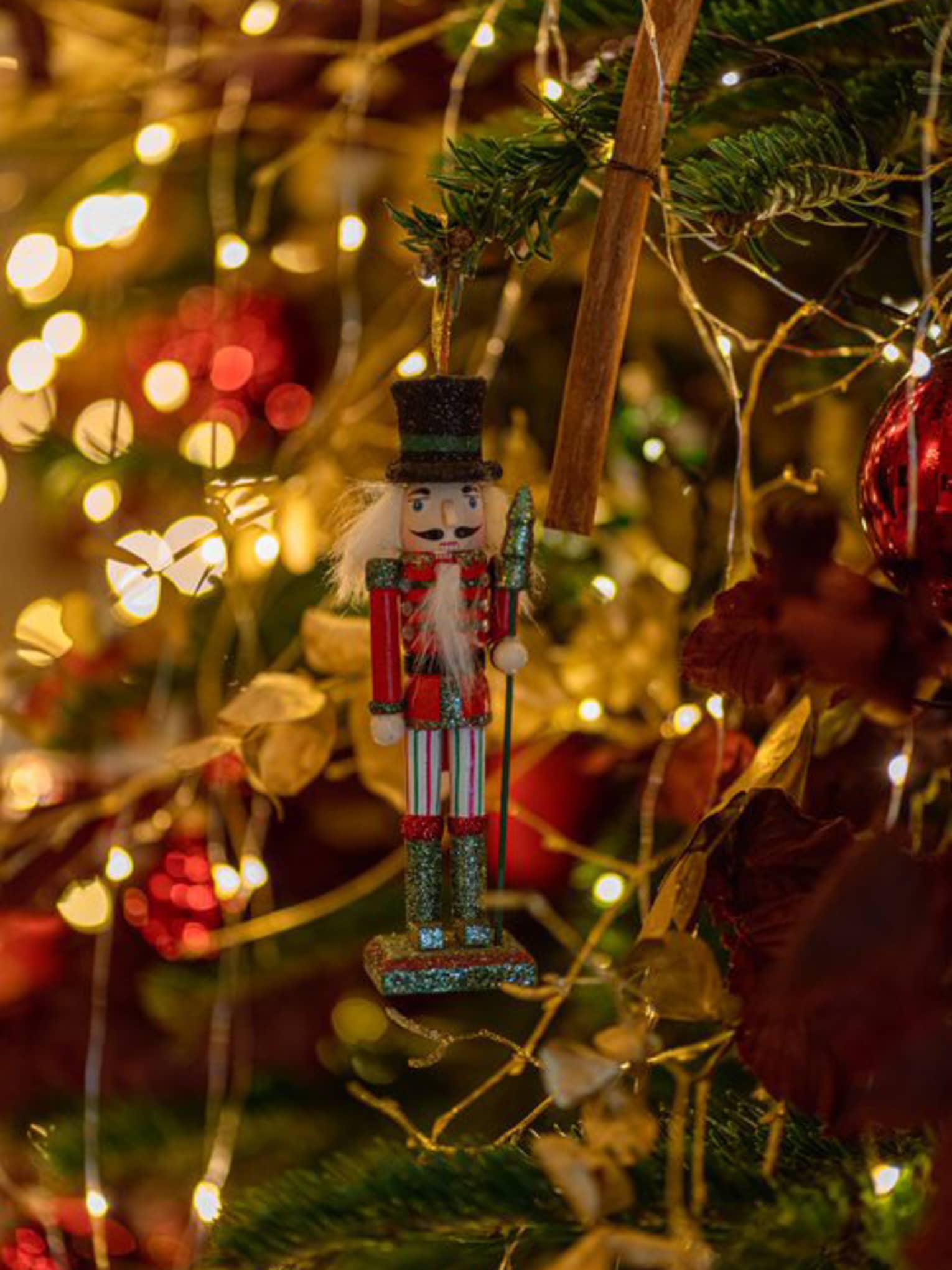 A nutcracker ornament on a Christmas tree.