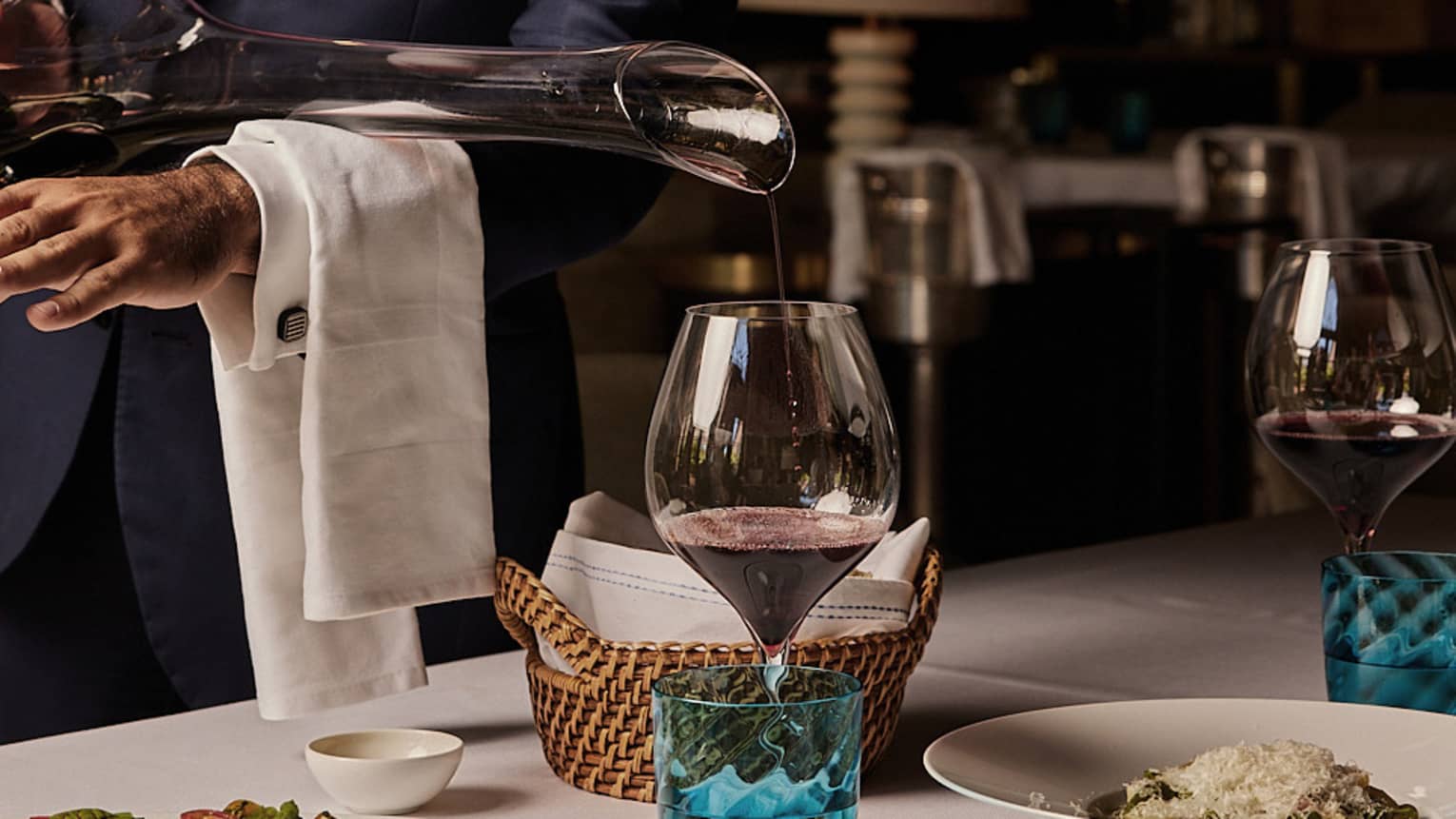 Red wine being poured into a glass from a long-necked decanter